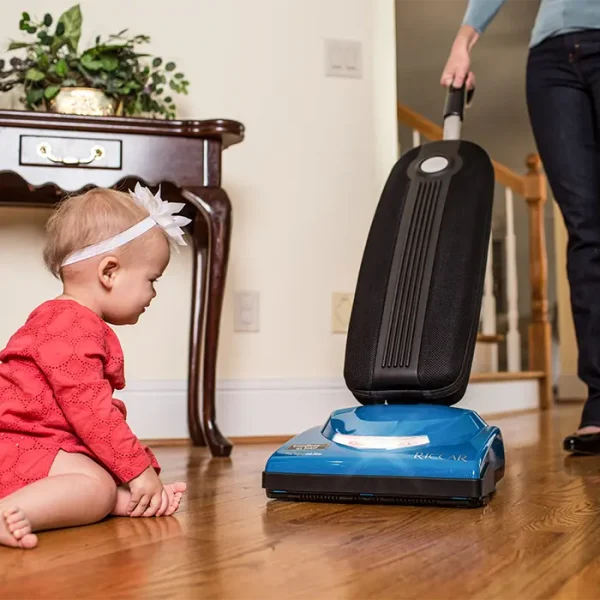Vacuuming a hardwood floor with a Riccar Cordless SupraLite Vacuum near a baby