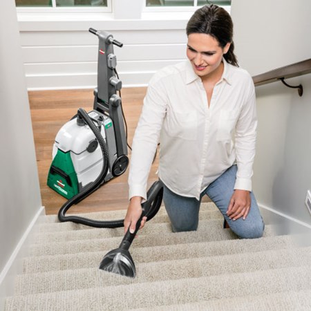 Woman cleaning the carpet on a stairway with a corded Vacuum cleaner