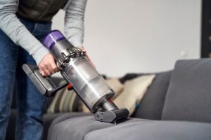 Person vacuuming couch - Stark's provides The Ultimate Holiday Cleaning Checklist: Preparing Your Home for Guests
